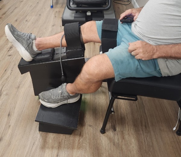 Side view of a patient seated for a Knee-on-Trac® session at McNamara Chiropractic Center in Lighthouse Point, FL, with thigh and calf straps secured